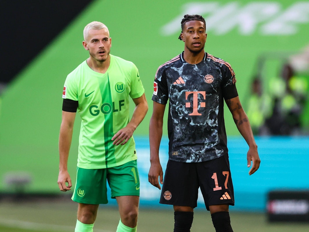 Jakub Kaminski und Michael Olise stehen beim Spiel des VfL Wolfsburg gegen den FC Bayern nebeneinander auf dem Platz.