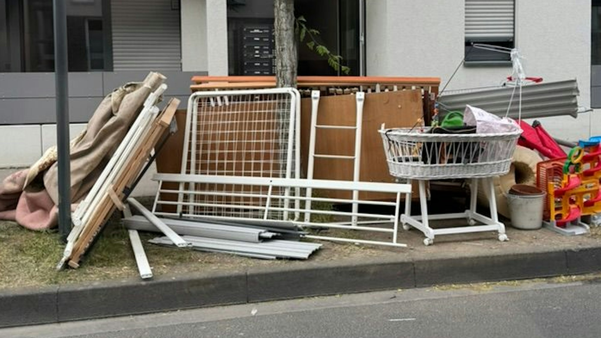 Müll, darunter eine Wiege und zwei Lattenroste stehen am Straßenrand.
