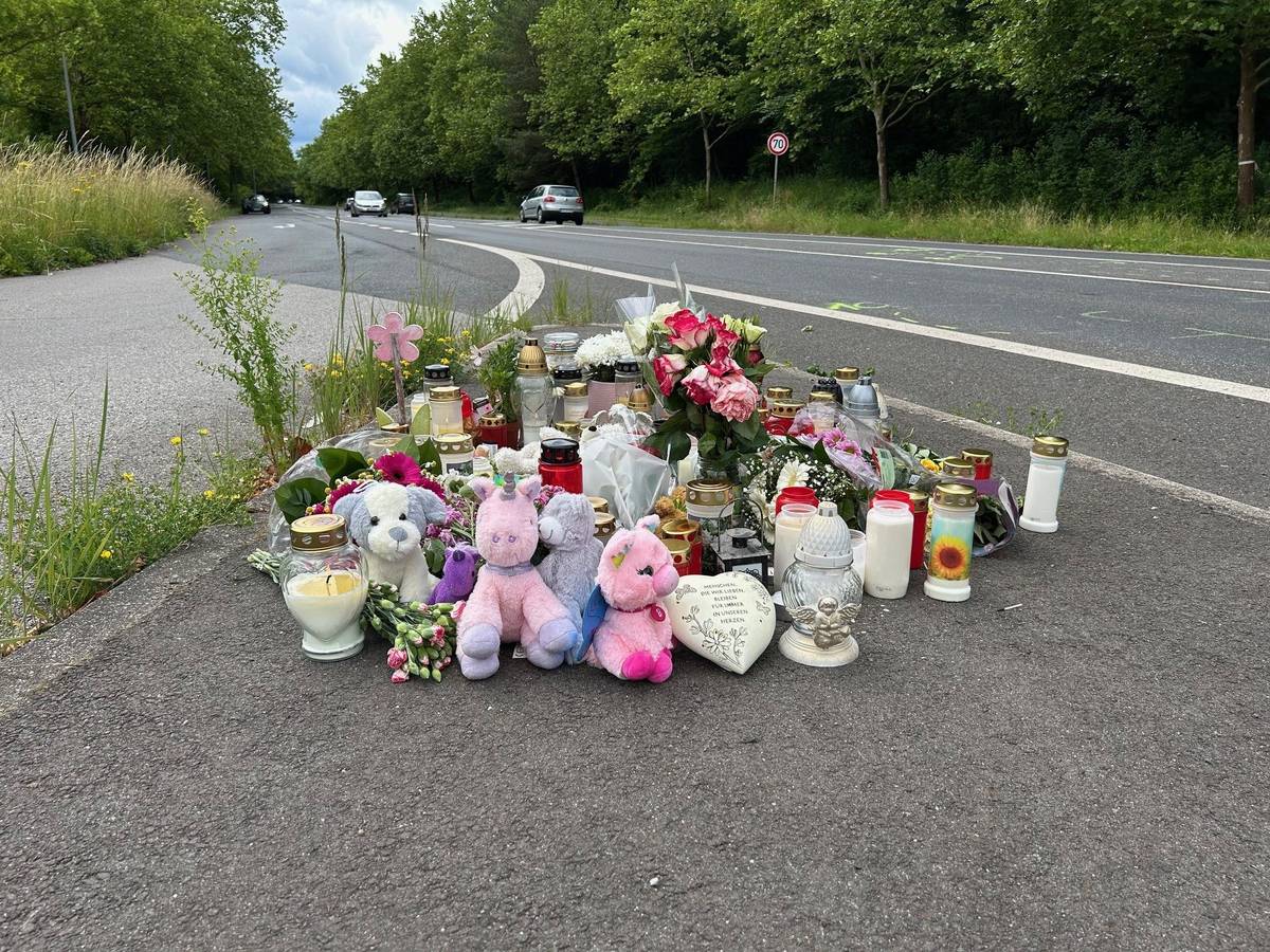 An einer Straße liegen Blumen und Plüschtiere, stehen zahlreiche Kerzen.
