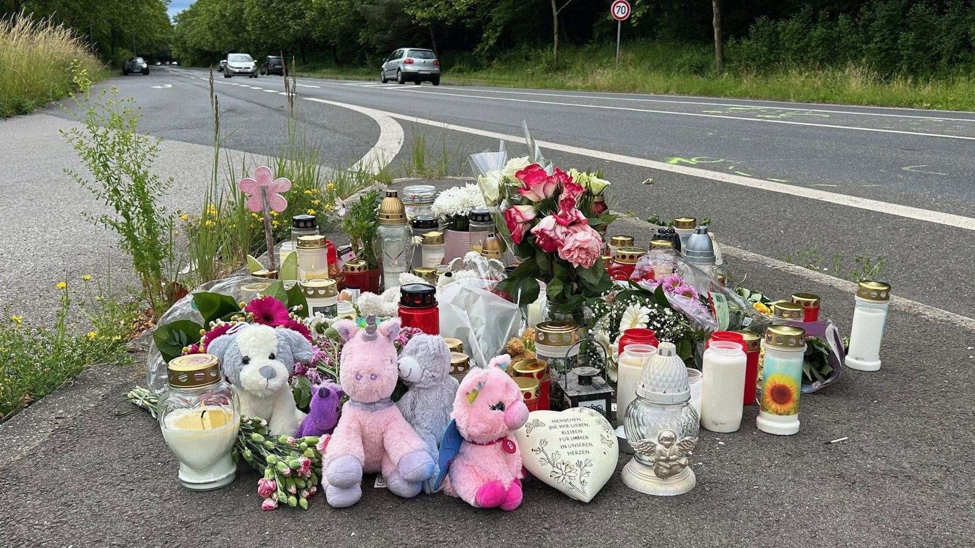 An einer Straße liegen Blumen und Plüschtiere, stehen zahlreiche Kerzen.