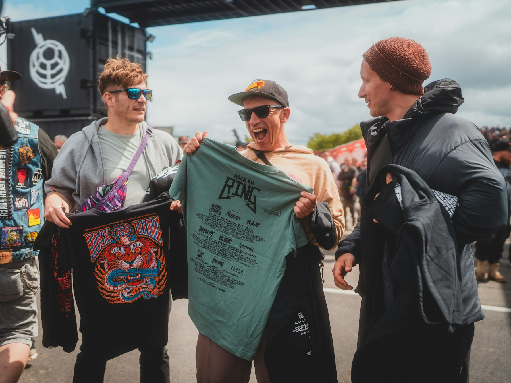 Nils Plum, Bastian Campmann und Flo Peil halten T-Shirts hoch.