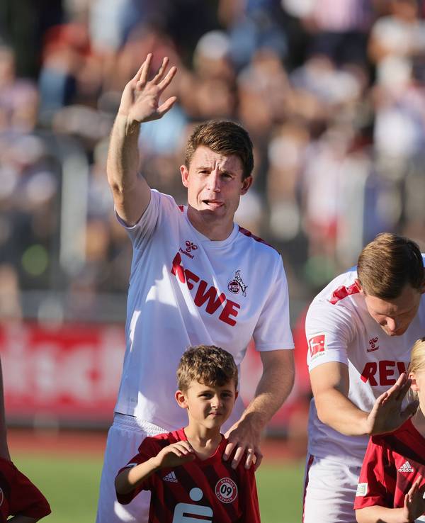 Dominique Heintz winkt auf die Tribüne, Luca Kilian spricht mit seinem Einlaufkind.