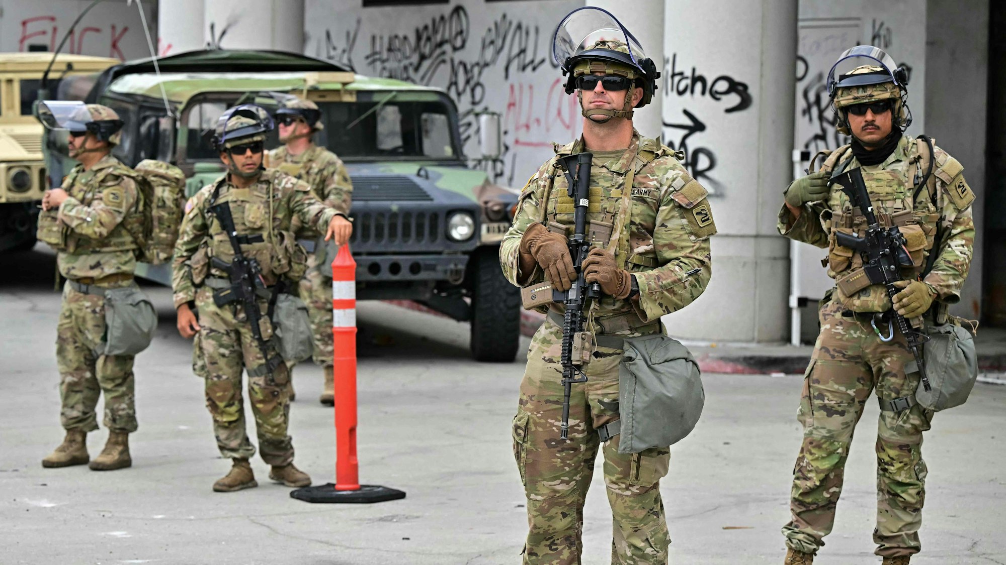Fünf schwer bewaffnete Soldaten stehen vor einem Gebäude.