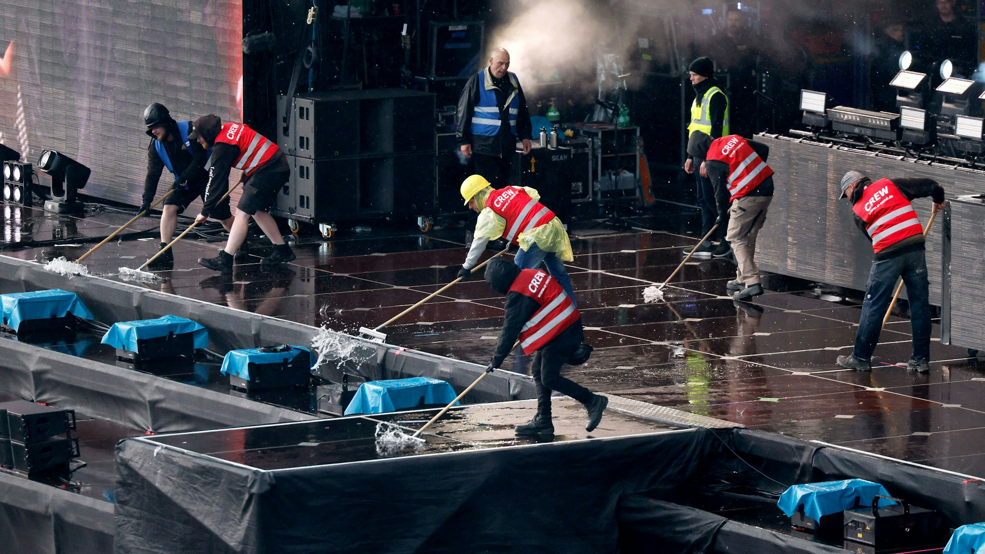 Crew-Mitglieder kehren Regenwasser von der Utopia Stage.