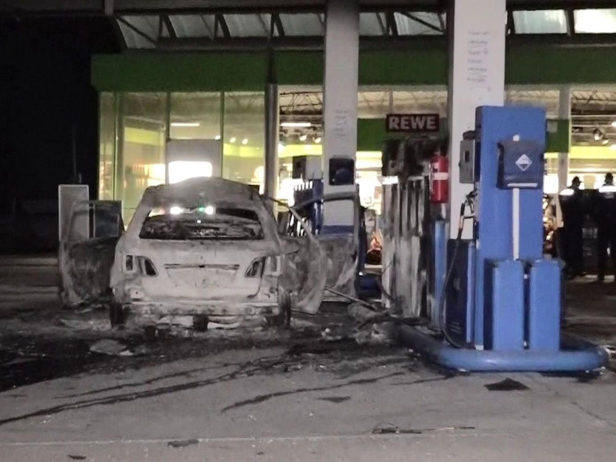 Ein ausgebranntes Fahrzeug steht an einer Zapfsäule auf einer Tankstelle in Hannover.