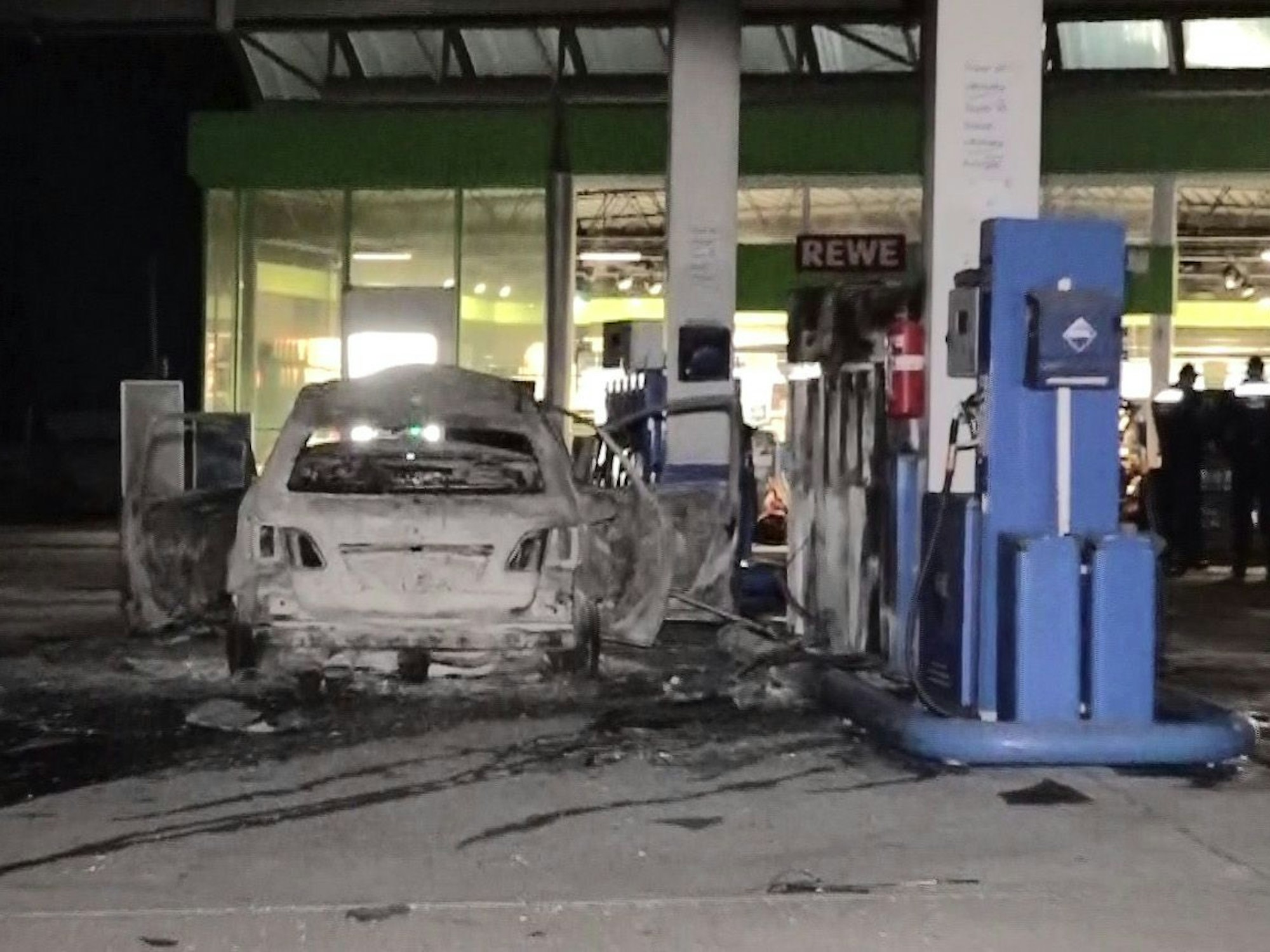 Ein ausgebranntes Fahrzeug steht an einer Zapfsäule auf einer Tankstelle in Hannover.