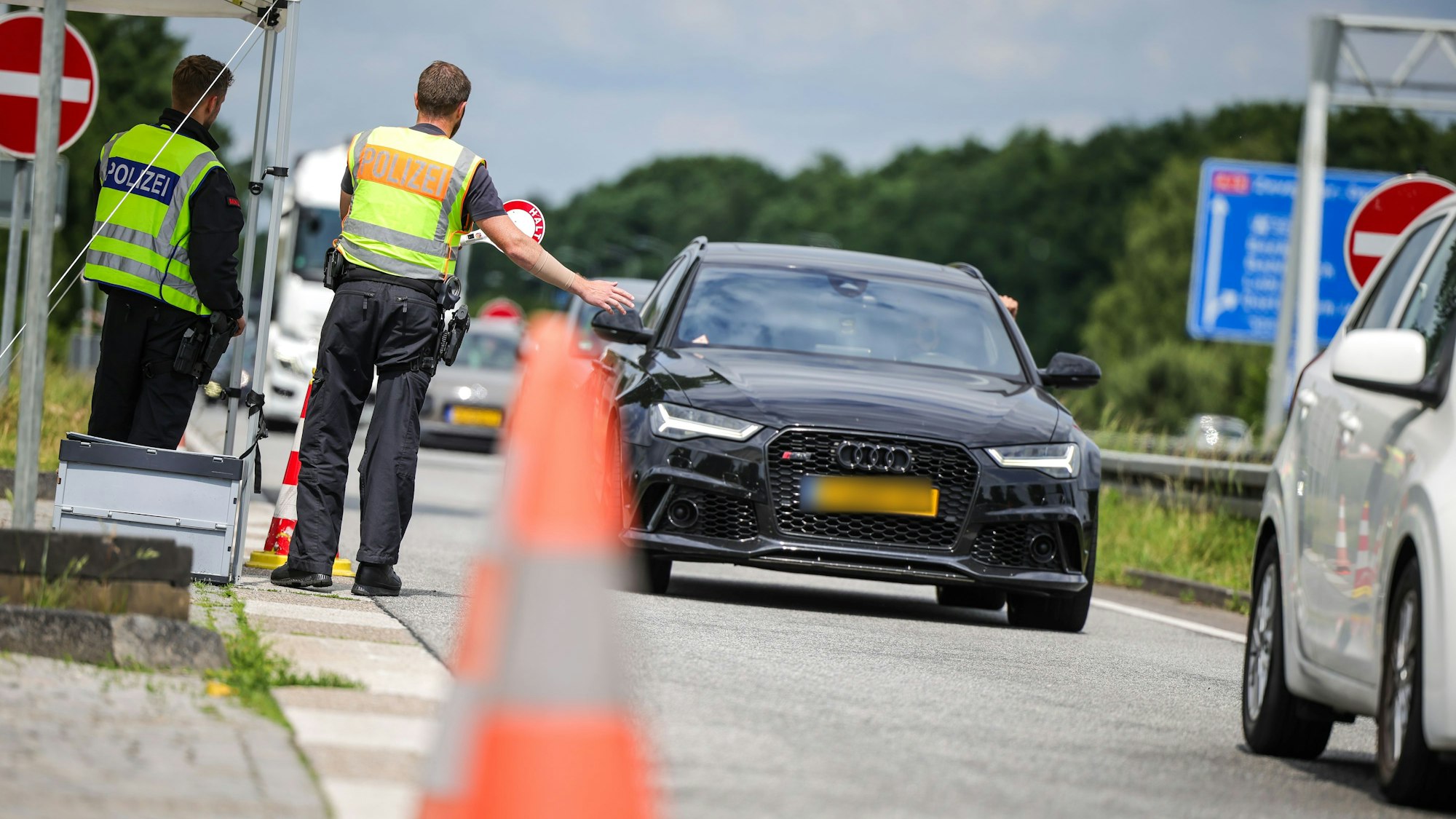 An der Grenze zu den Niederlanden auf der A3 in Emmerich kontrollieren zwei Bundespolizisten die nach Deutschland einfahrenden Fahrzeuge.
