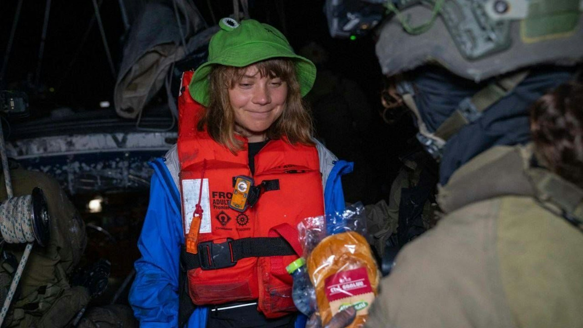 Klimaaktivisten Greta Thunberg strahlt. Ihr wird auf der „Selfie-Yacht der Promis“ ein Sandwich angeboten.
