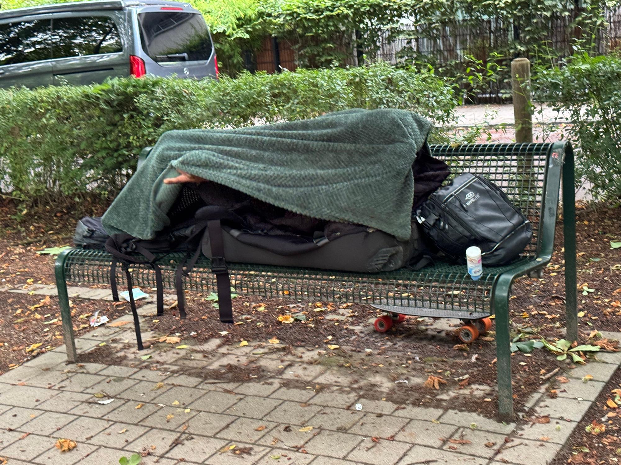 Am Rautenstrauch Kanal lebt ein Obdachloser auf einer Bank.
