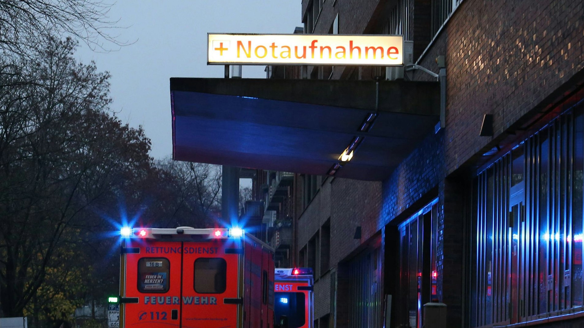 Rettungswagen mit Blaulicht stehen nachts vor einer Notaufnahme-