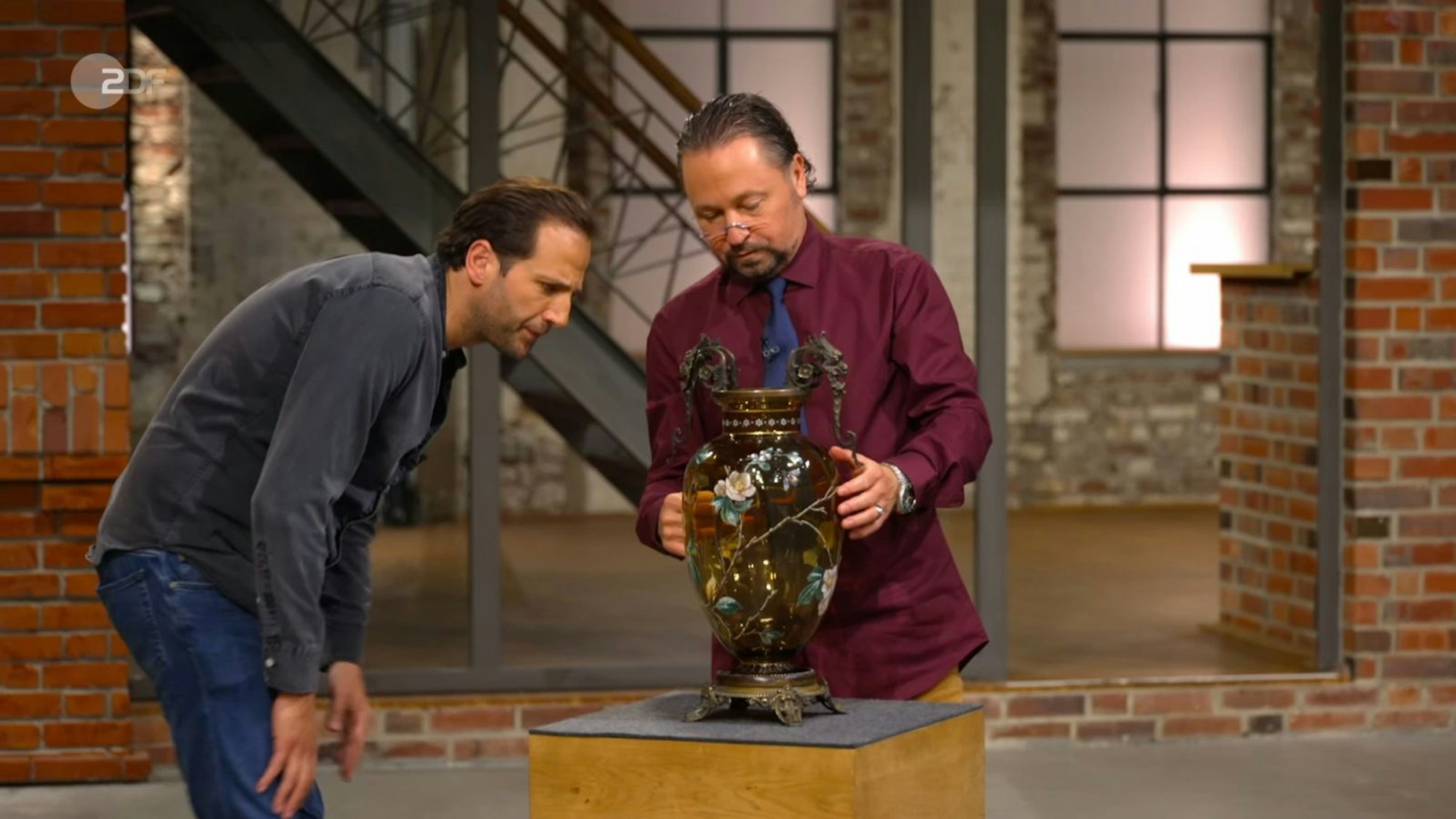 Wolfgang Pauritsch sah sich das Schmuckstück aus der Nähe an: „Das Glas ist mindestens 100 Jahre alt und wunderschön bemalt.“ Walter Lehnertz bat aus der Ferne: „Klopf mal, ob die ganz ist.“ Pauritsch tat dies. Julian Schmitz-Avila tippte auf eine böhmische Herkunft. (Bild: ZDF)