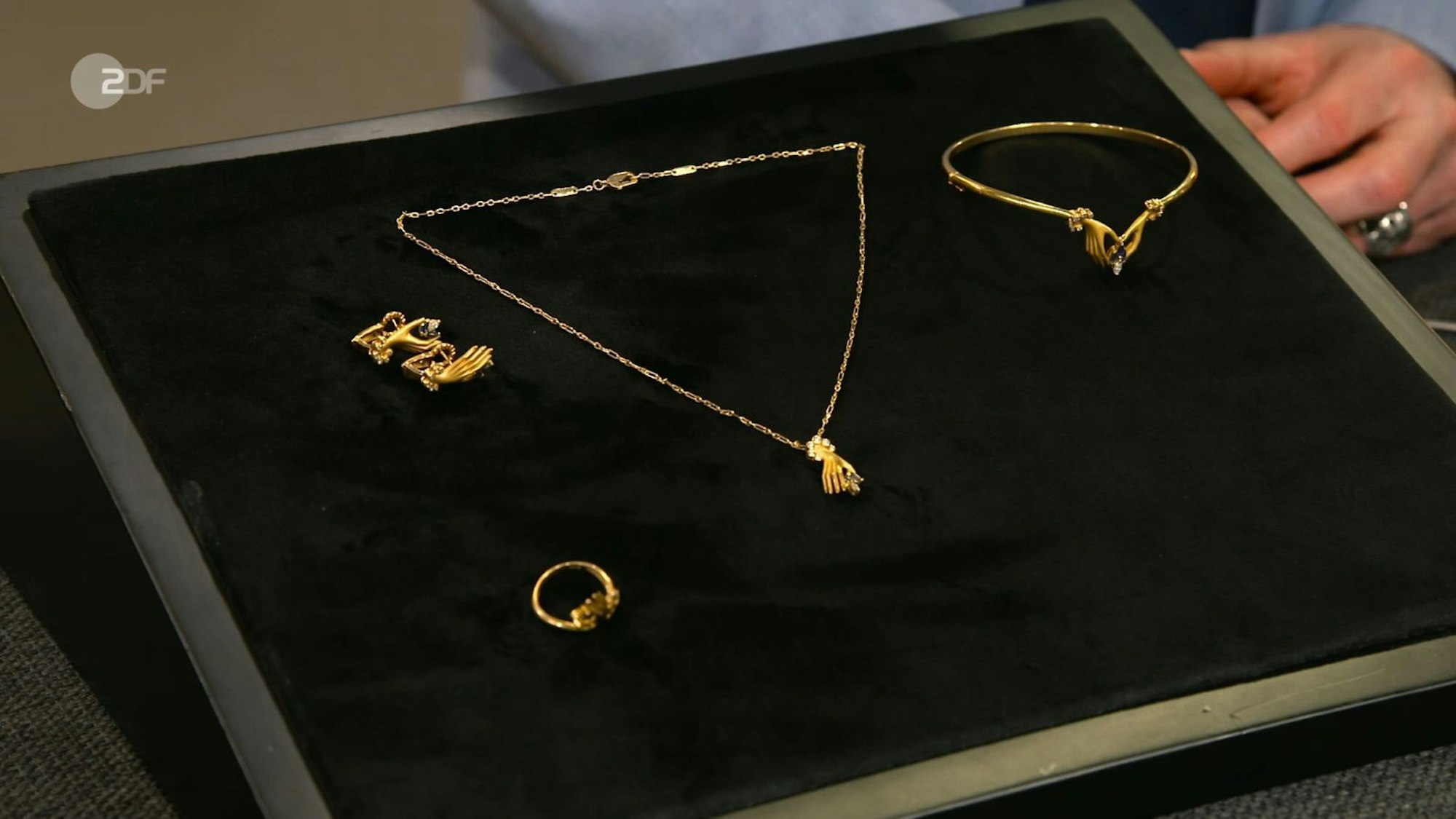Wieso Hände als Motive? Das Design des Schmucksets mit Diamanten und Saphiren konnte Lichter nicht nachvollziehen. Patrick Lessmann lobte das „Design, das im Gedächtnis bleibt“. Den Wunschpreis von 2.500 Euro korrigierte Lessmann auf 4.500. Schmitz-Avila bezahlte 4.020. (Bild: ZDF)