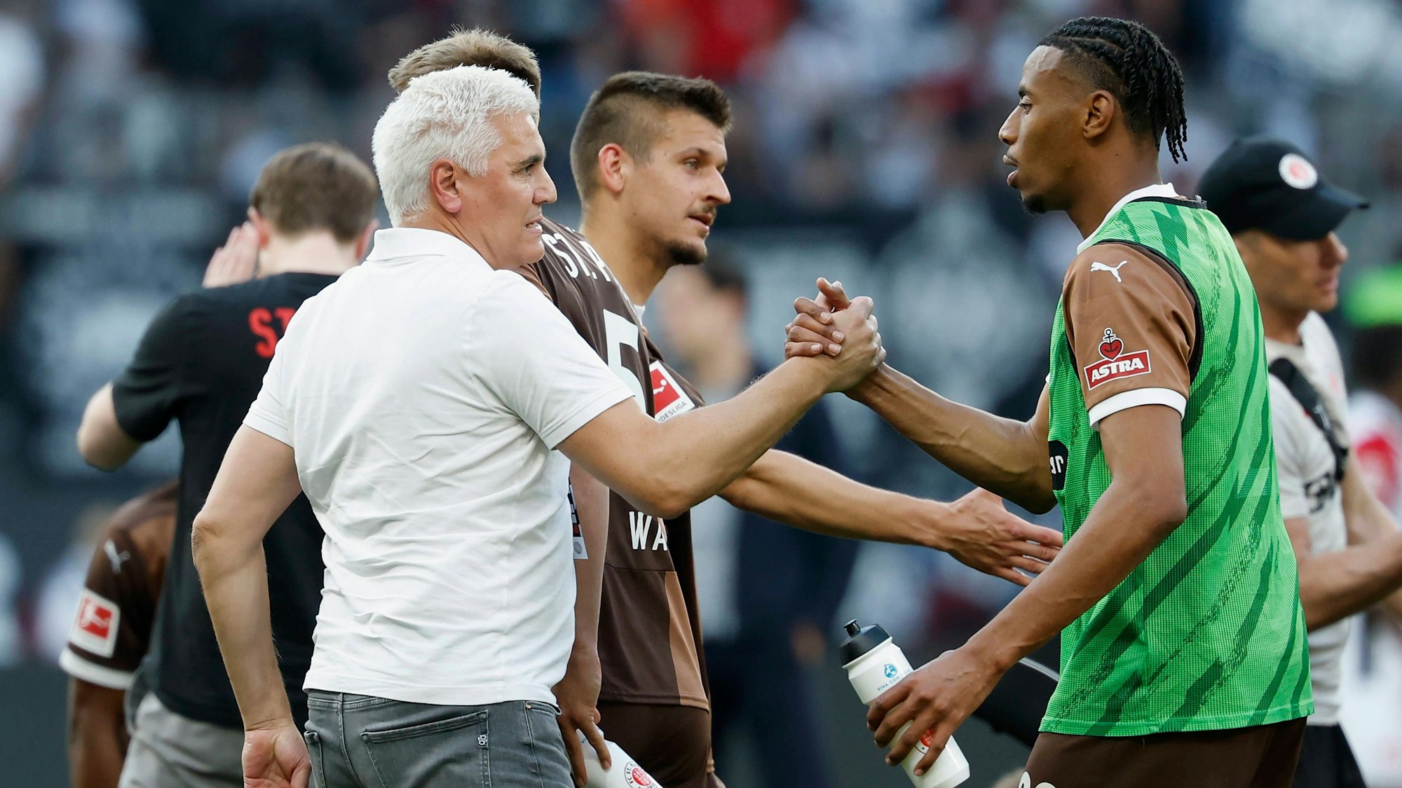 Sport-Chef Andreas Bornemann vom FC St. Pauli gibt Stürmer Morgan Guilavogui die Hand.