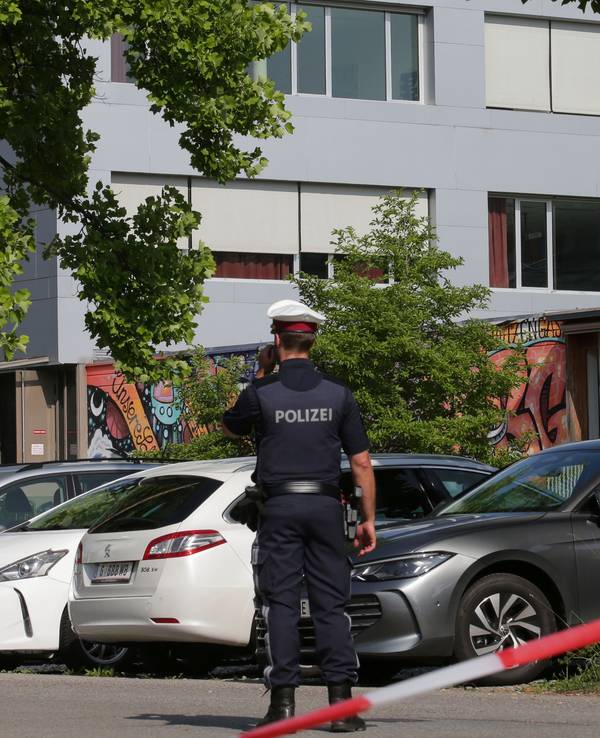 Ein Polizeibeamter telefoniert vor dem Schulgebäude.