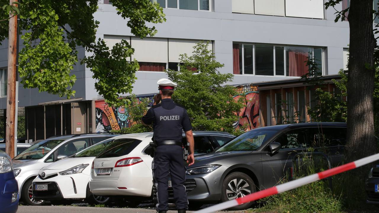 Ein Polizeibeamter telefoniert vor dem Schulgebäude.