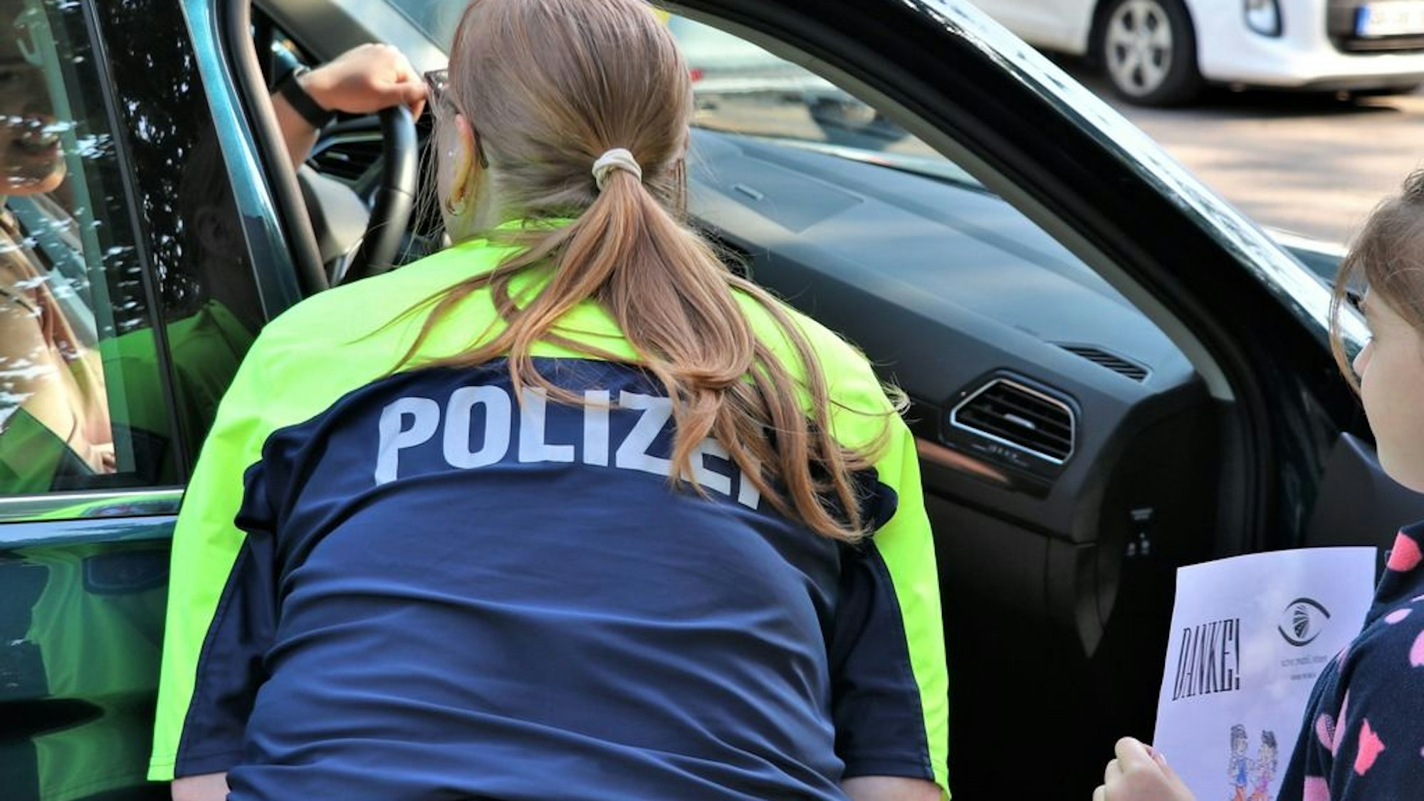 Im Rahmen der landesweiten Dank- und Denkzettel-Aktion kontrollieren Polizeibeamte gemeinsam mit Schulkindern den Verkehr im Umfeld der Andreasschule in Korschenbroich-Pesch.