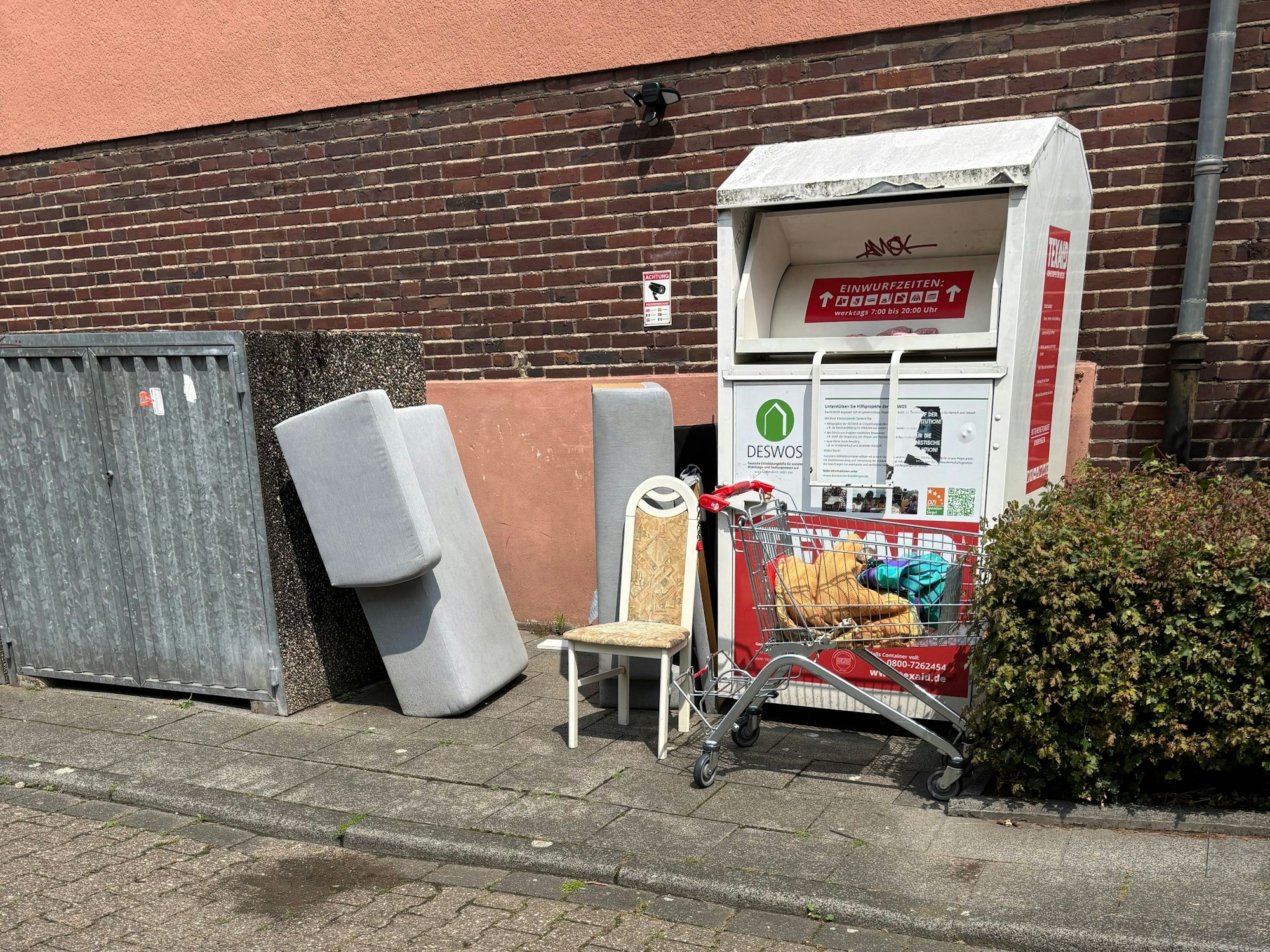 Sperrmüll liegt neben Mülltonnen.