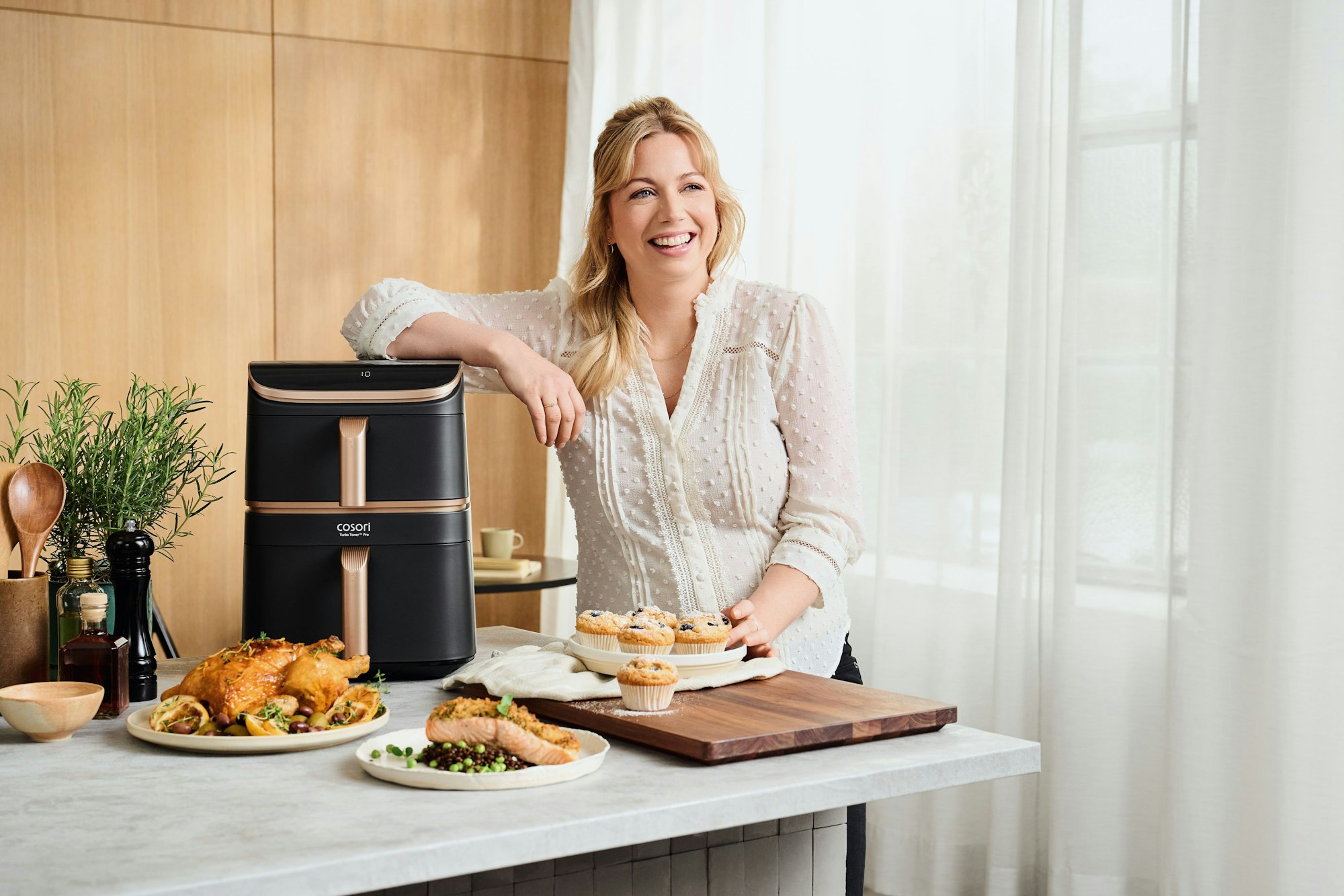 Zora Klipp mit verschiedenen Gerichten neben einer Cosori Heißluftfritteuse.