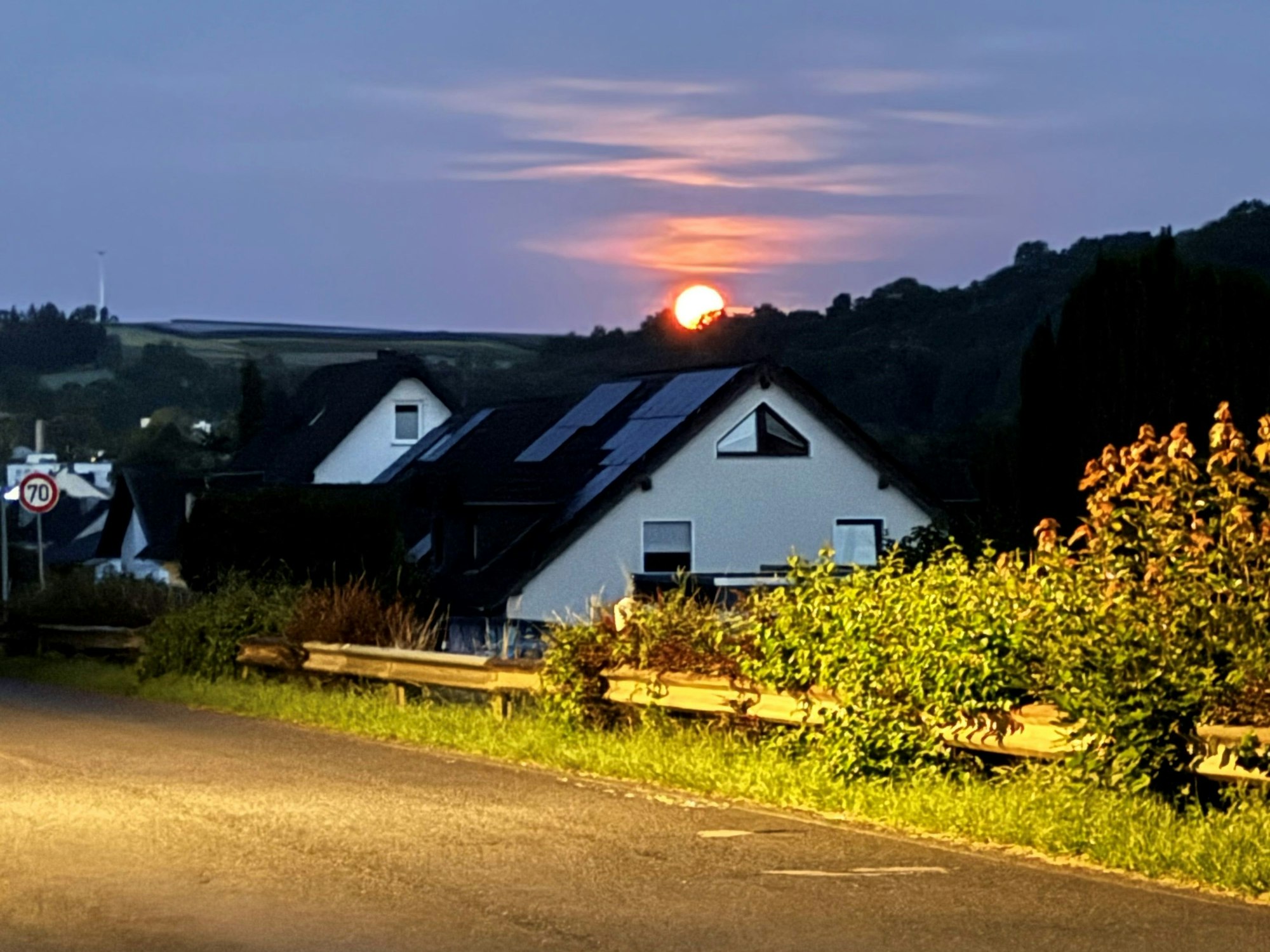 Der Mond geht hinter einem Hügel unter.