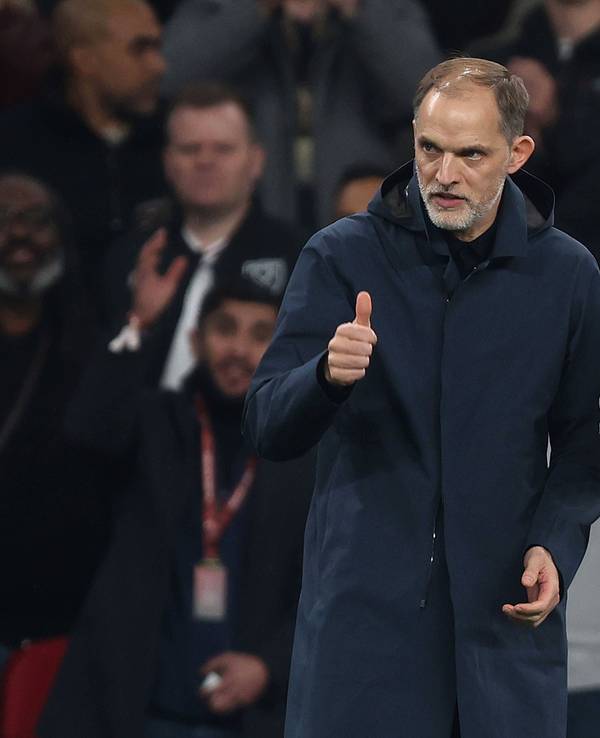 Thomas Tuchel zeigt einem Spieler auf dem Feld „Daumem hoch“, während neben ihm Jude Bellingham steht.