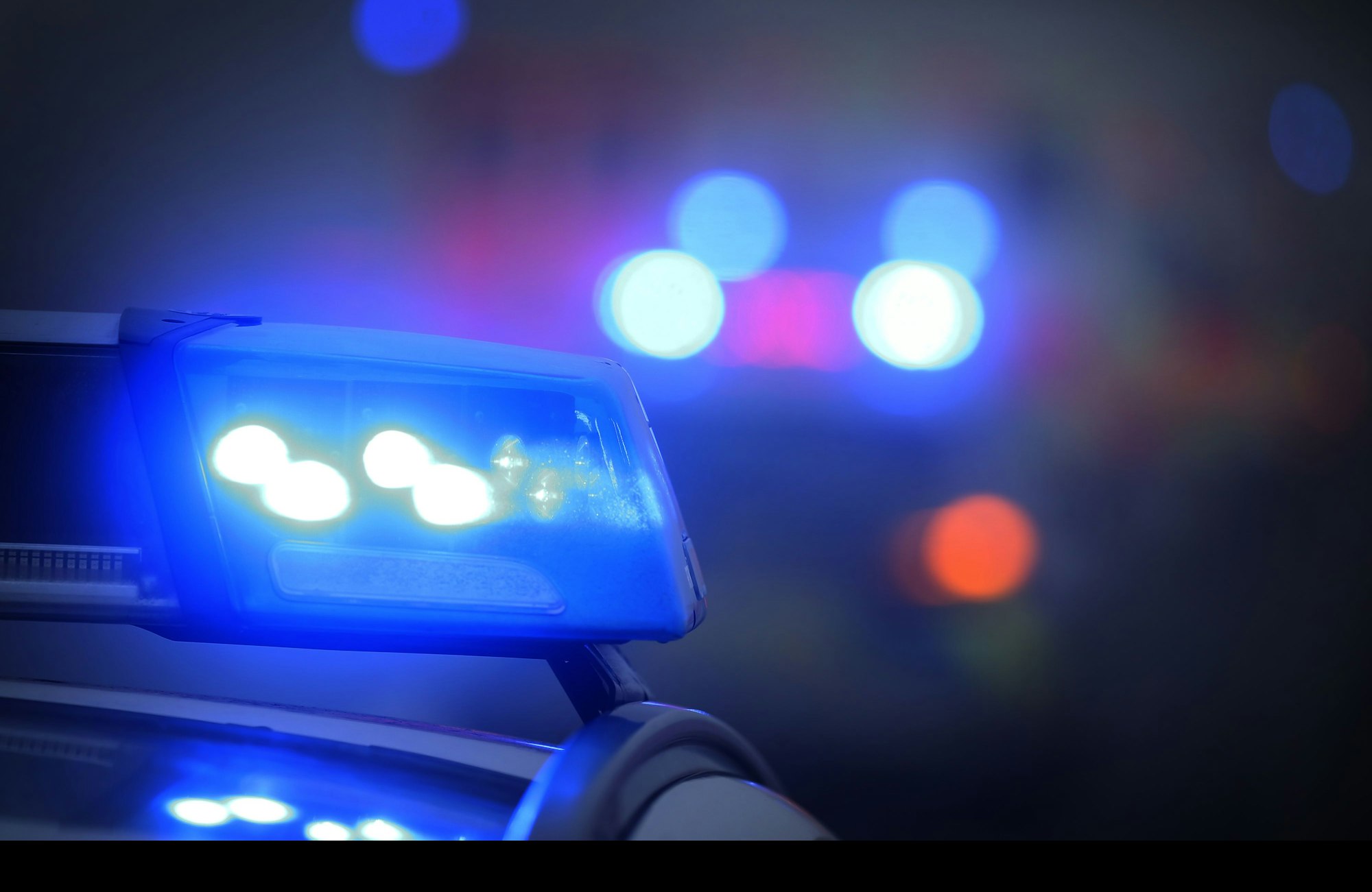 Ein Polizeiauto mit eingeschaltetem Blaulicht steht an einer Unfallstelle.