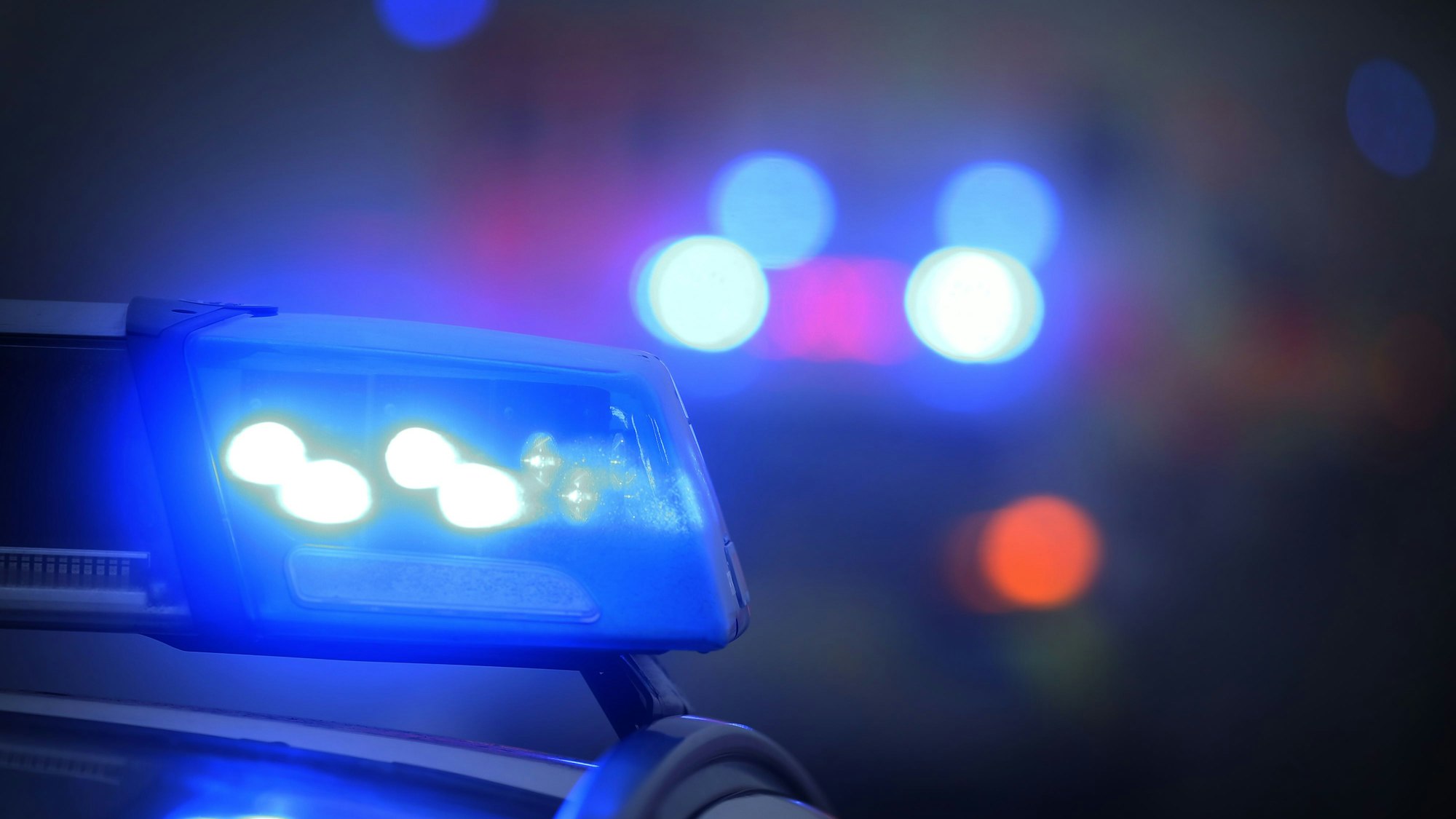 Ein Polizeiauto mit eingeschaltetem Blaulicht steht an einer Unfallstelle.