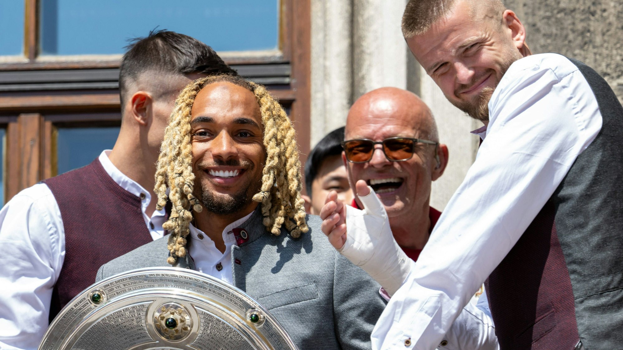 Sacha Boey posiert bei der Titelfeier des FC Bayern mit der Meisterschale.