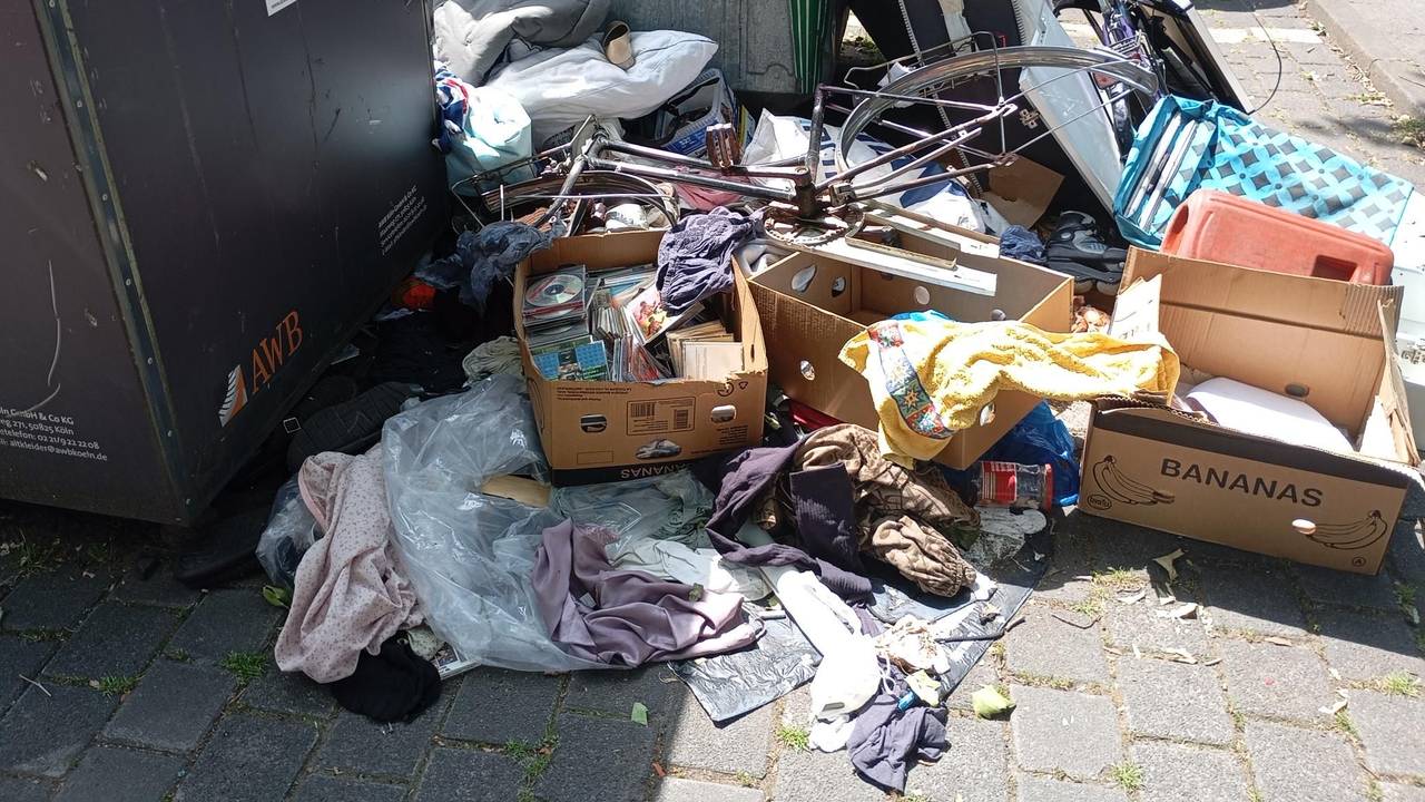 Vor Altkleider- und Glascontainern liegen Wäschestücke, eine Kiste mit CDs und Fahrräder ohne Reifen rum.