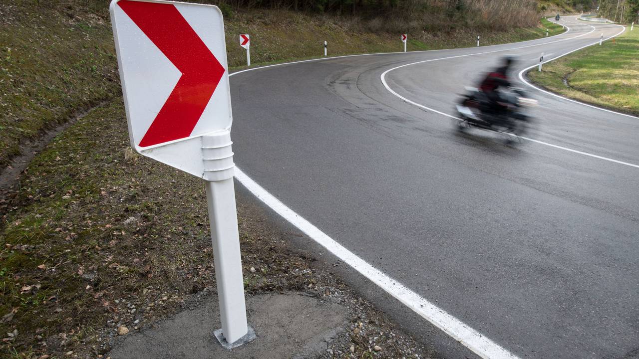 Ein Motorrad fährt auf einer Landstraße in einer Kurve.