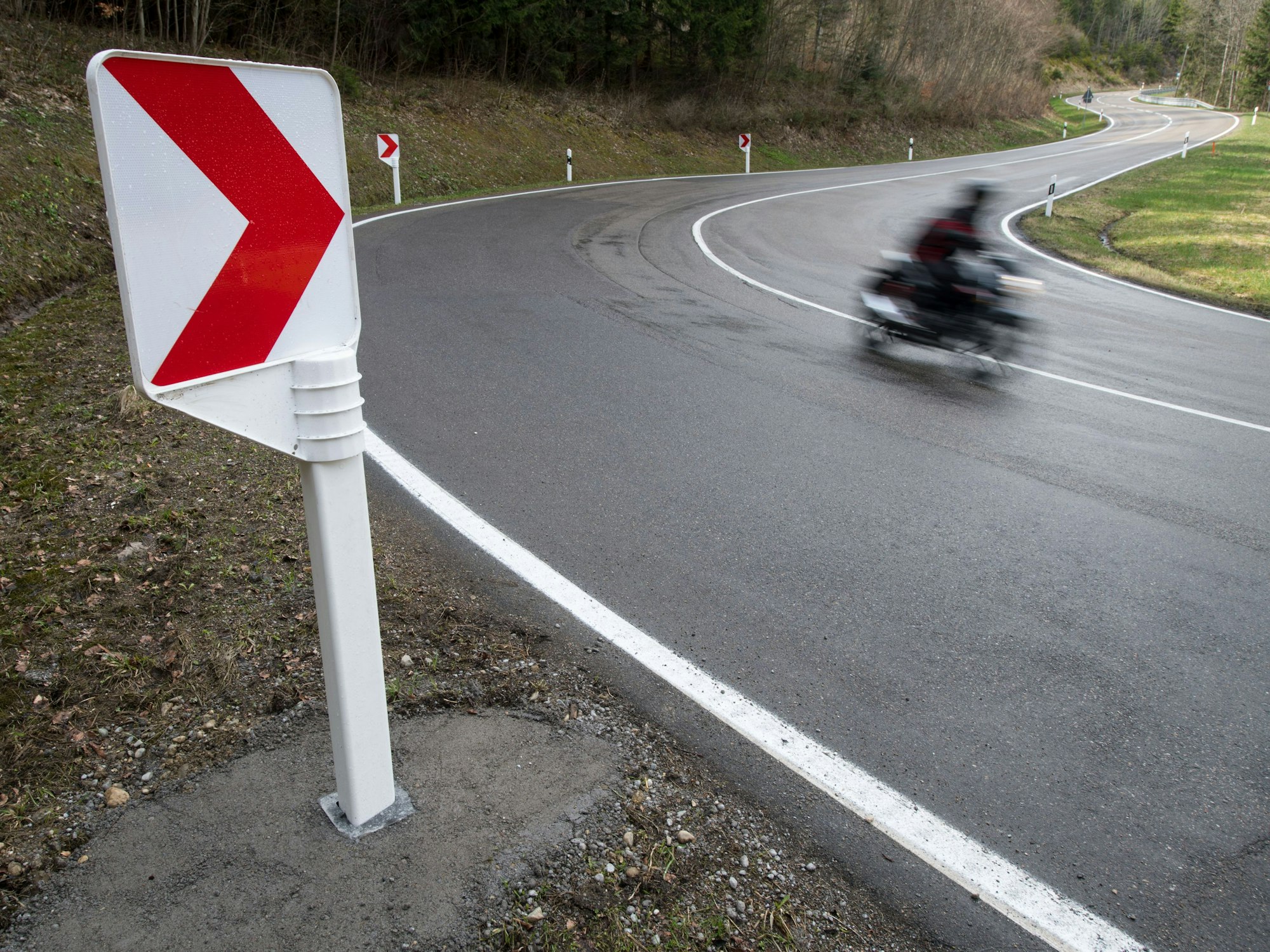 Ein Motorrad fährt auf einer Landstraße in einer Kurve.