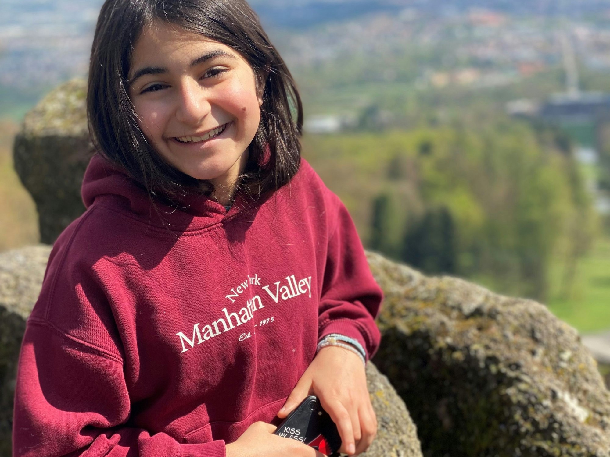 Ein Mädchen steht an einer Felsbrüstung.