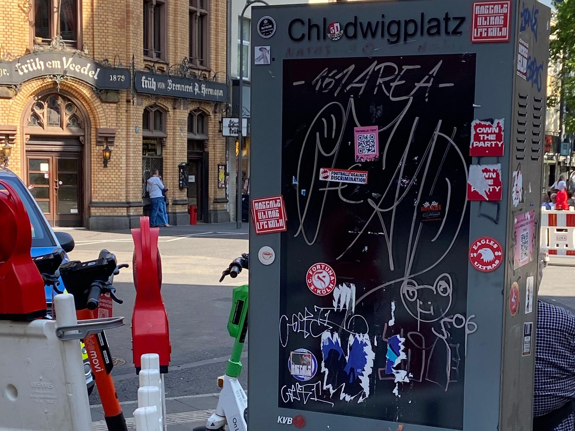 Eine Infosäule an einer Straße ist beschmiert und mit Aufklebern beklebt.