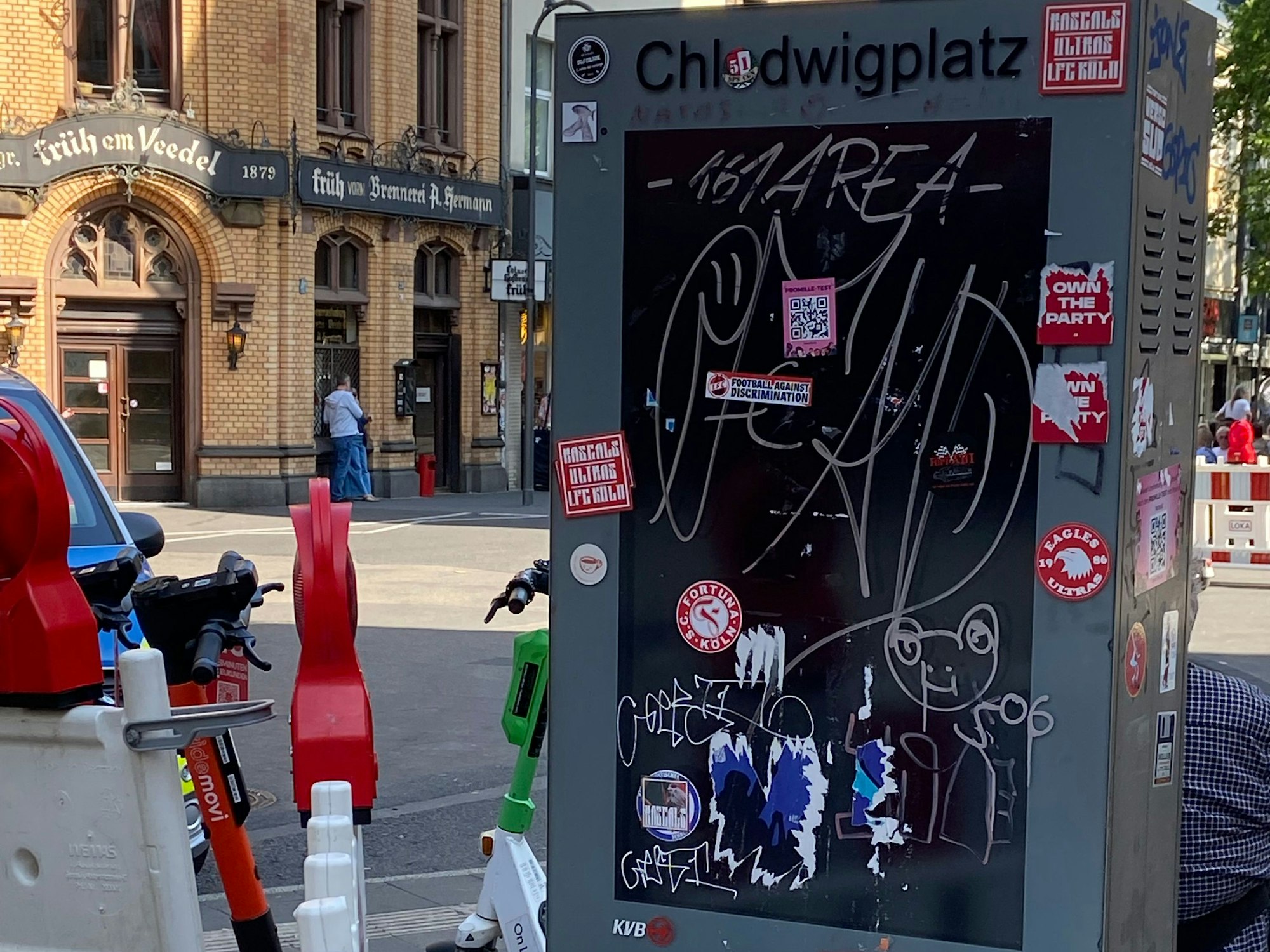 Eine Infosäule an einer Straße ist beschmiert und mit Aufklebern beklebt.