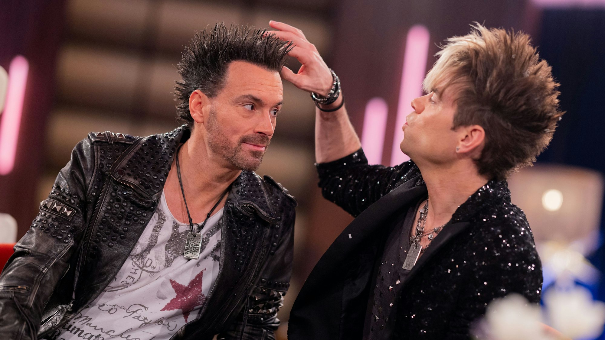 Ein Mann fasst die Haare eines anderen Mannes an.