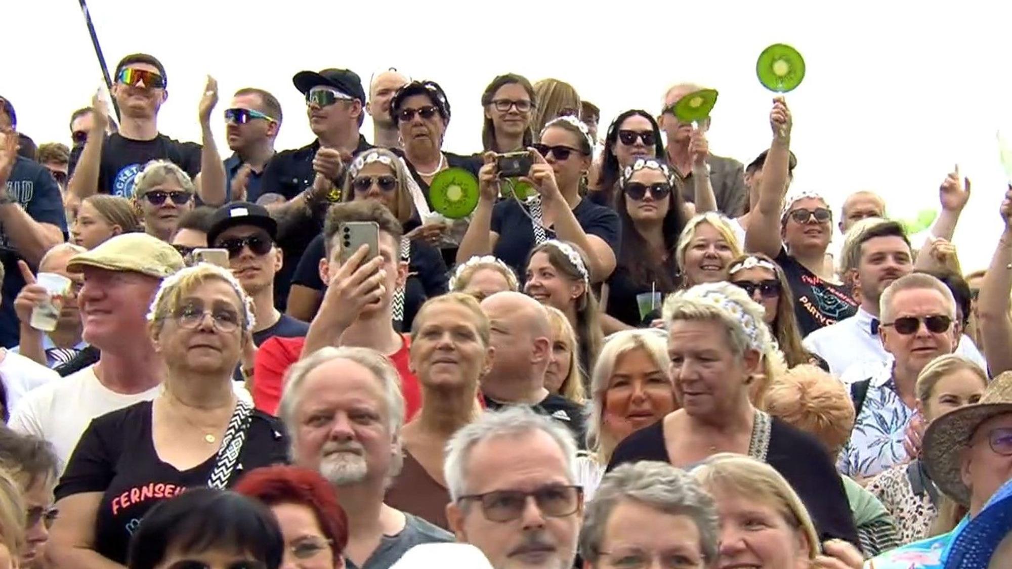 Die Fans vermissen Andrea Kiewel und halten Papp-Früchten hoch.