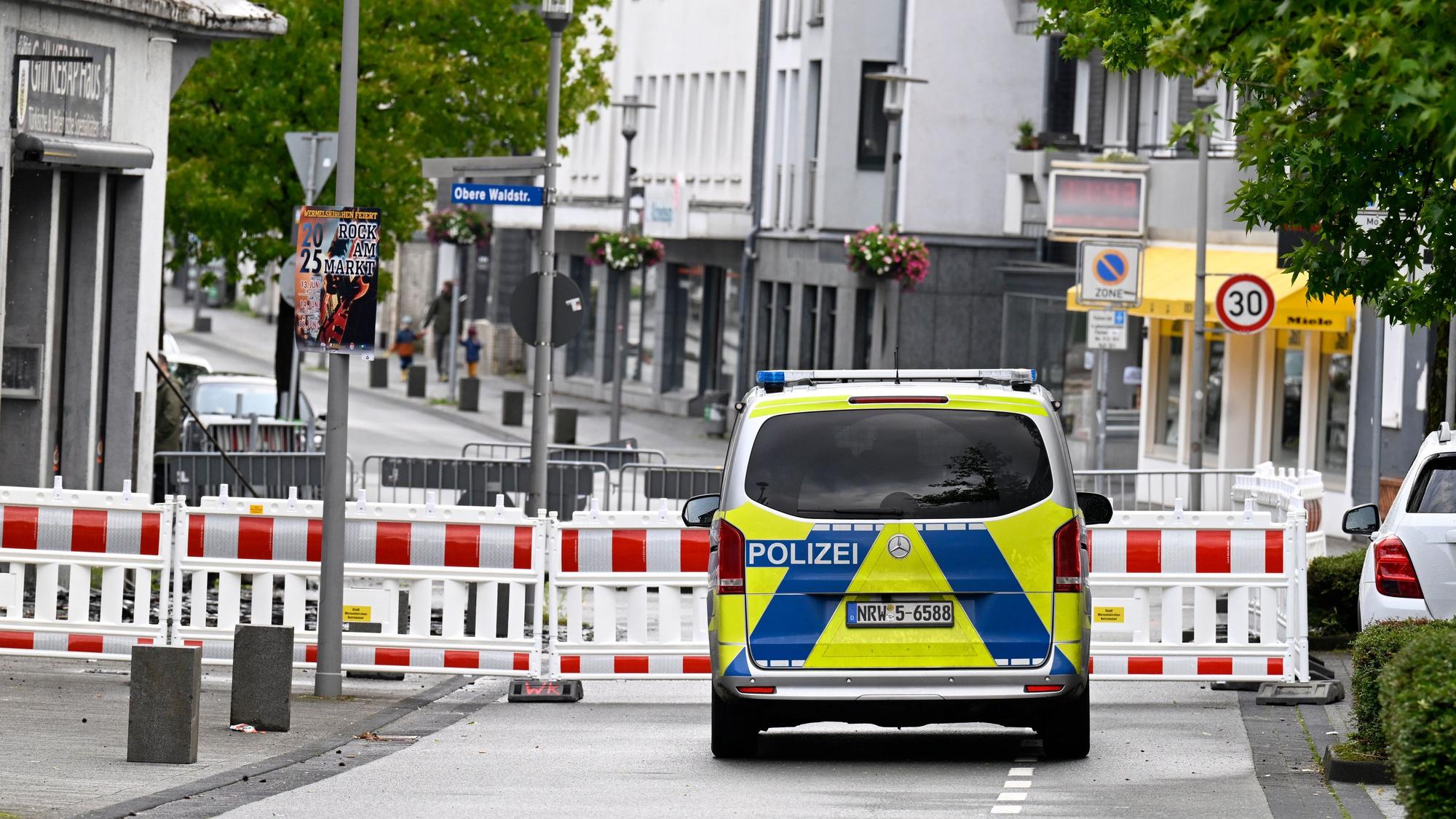 Eine Straße ist mit Warnbarken gesperrt, davor steht ein Polizeifahrzeug.