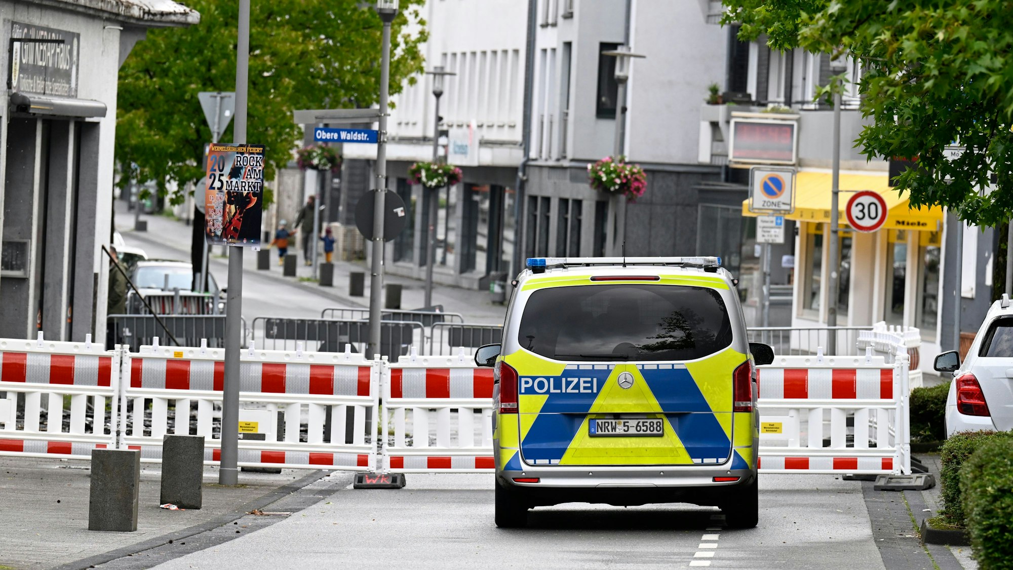 Eine Straße ist mit Warnbarken gesperrt, davor steht ein Polizeifahrzeug.