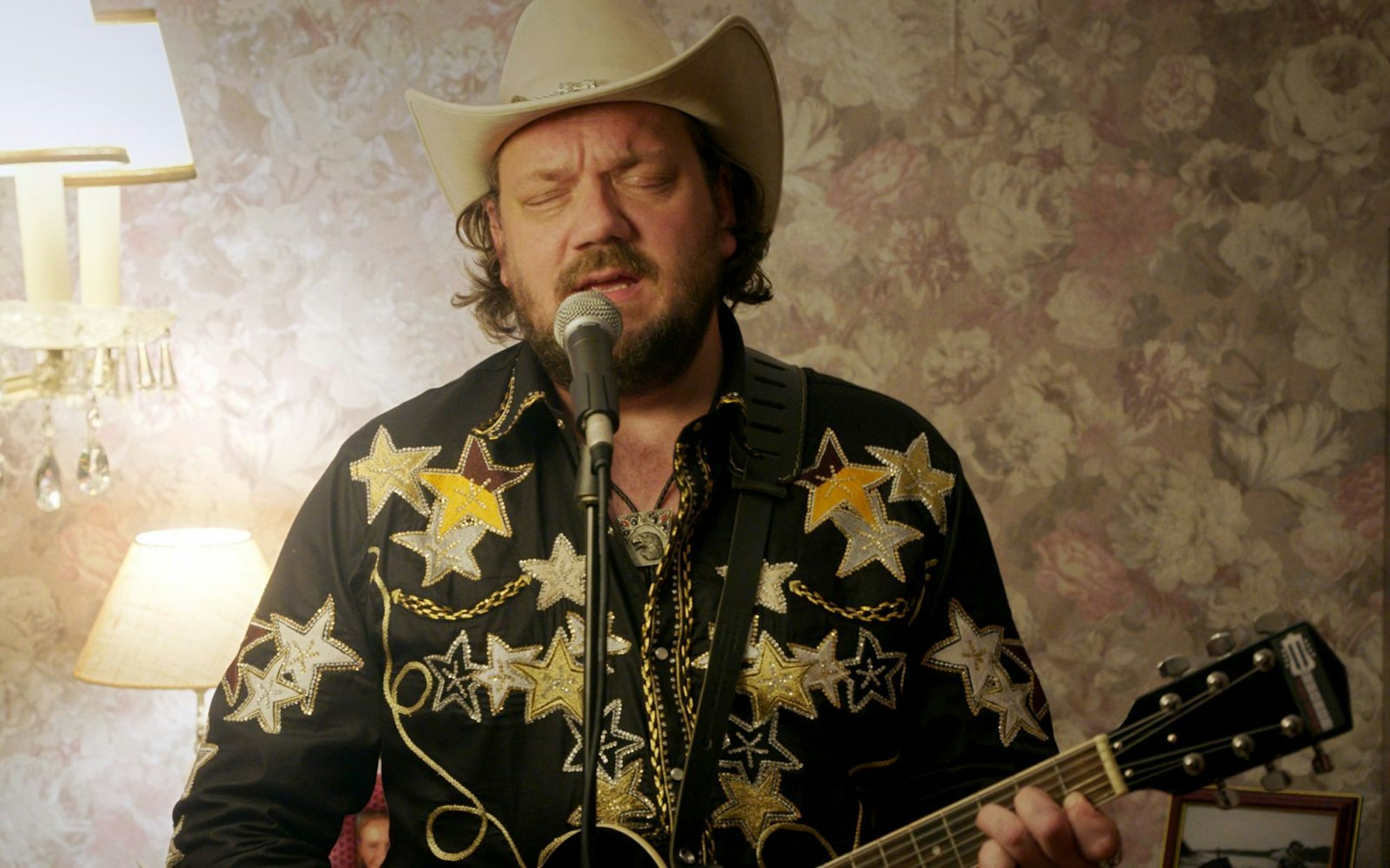 Der abgehalfterte Country-Schlagerstar Jeff Kanter (Charly Hübner) spielt in David Schalkos Anthologie-Serie „Warum ich?“ Wohnzimmerkonzerte bei fremden Leuten. Dabei hat er in der Episode „Cowboys“ eine verstörende Begegnung. (Bild: ARD Degeto Film/Superfilm Filmproduktions GmbH)