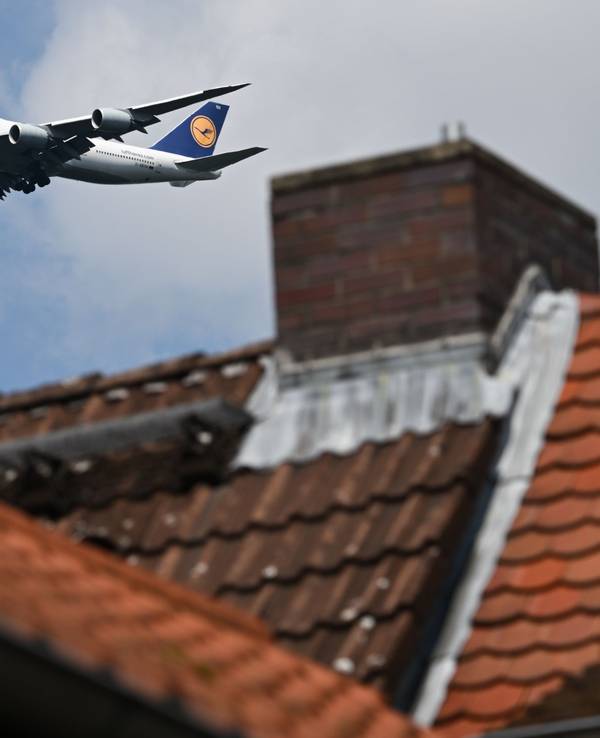 Eine Boeing 747-830 der Lufthansa ist hinter einem Haus im Landeanflug auf den Frankfurter Flughafen.
