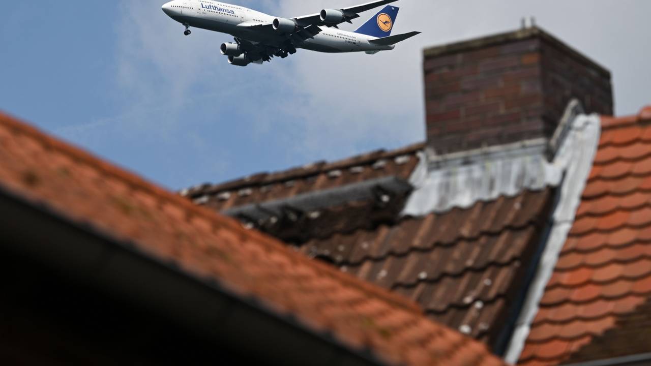 Eine Boeing 747-830 der Lufthansa ist hinter einem Haus im Landeanflug auf den Frankfurter Flughafen.