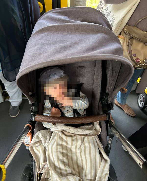 Ein Kind sitzt in einem Kinderwagen.