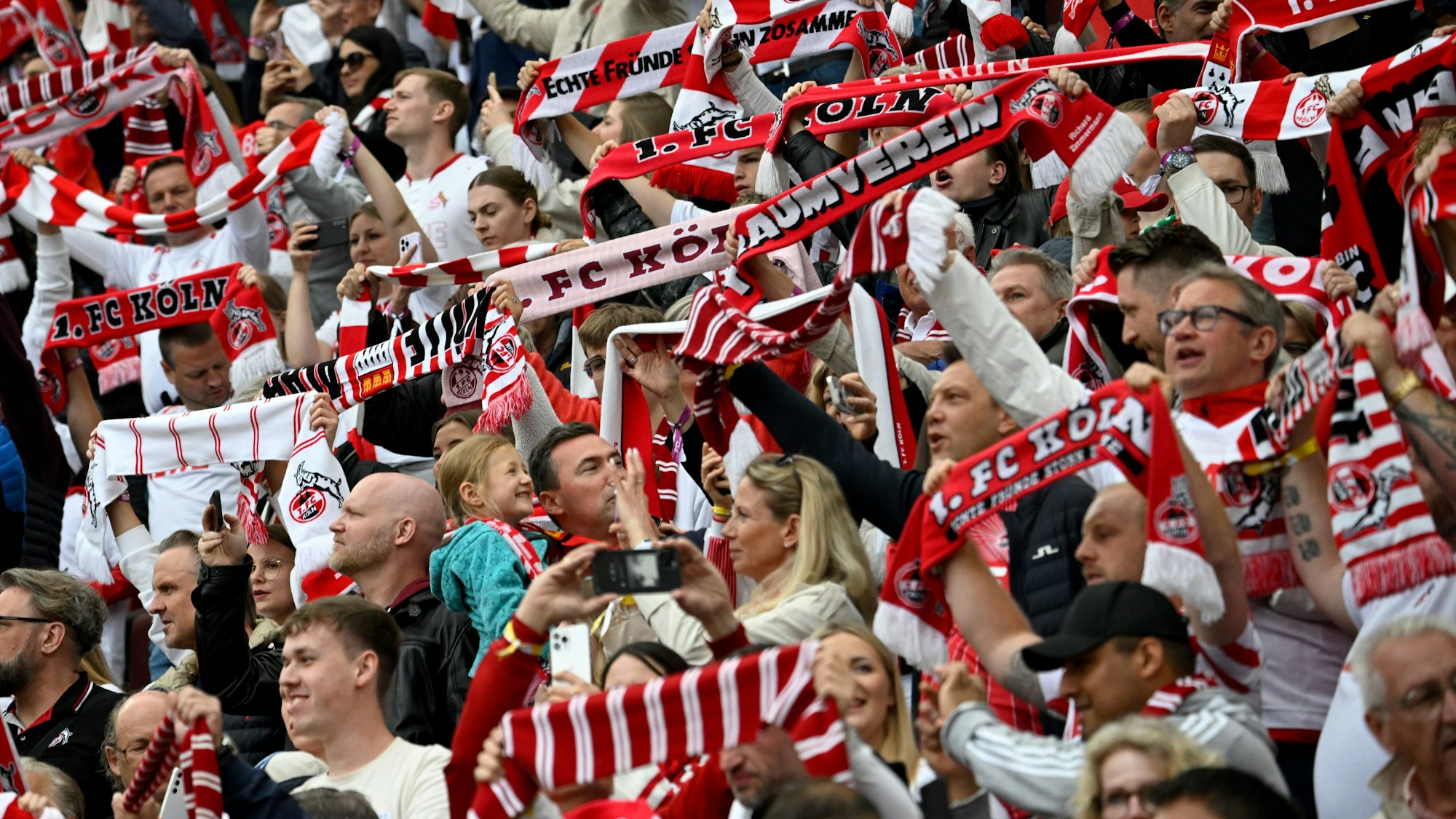 Kölner Fans halten zu Spielbeginn ihre Fanschals hoch.