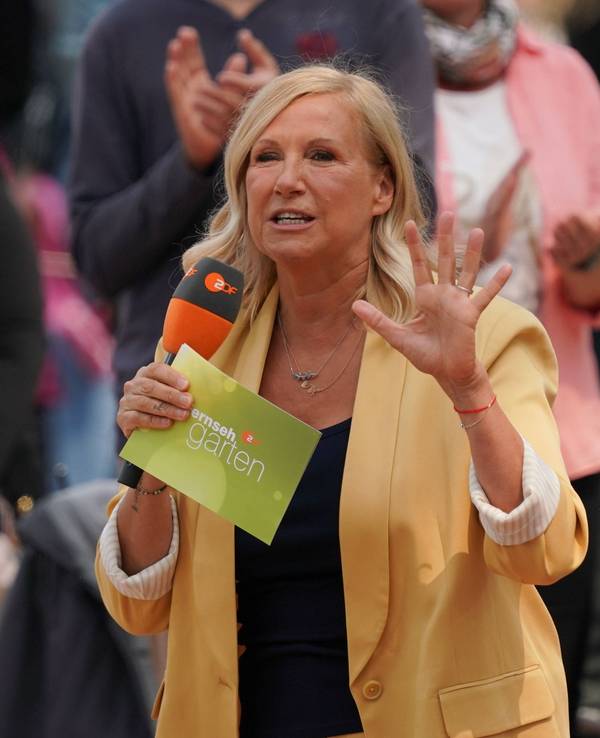Andrea Kiewel bei der „Fernsehgarten“-Sendung am 8. Juni 2025 mit Mikrofon und Moderationskarten in den Händen.