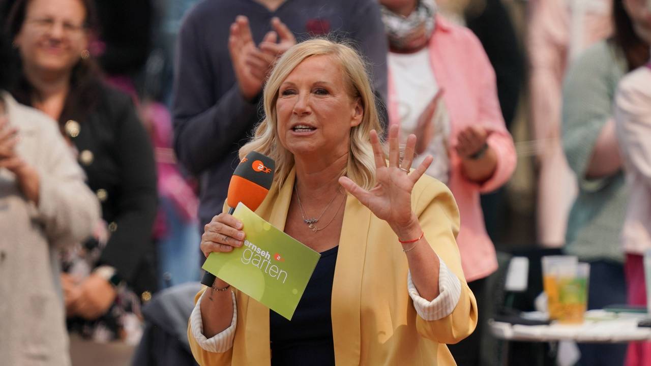 Andrea Kiewel bei der „Fernsehgarten“-Sendung am 8. Juni 2025 mit Mikrofon und Moderationskarten in den Händen.