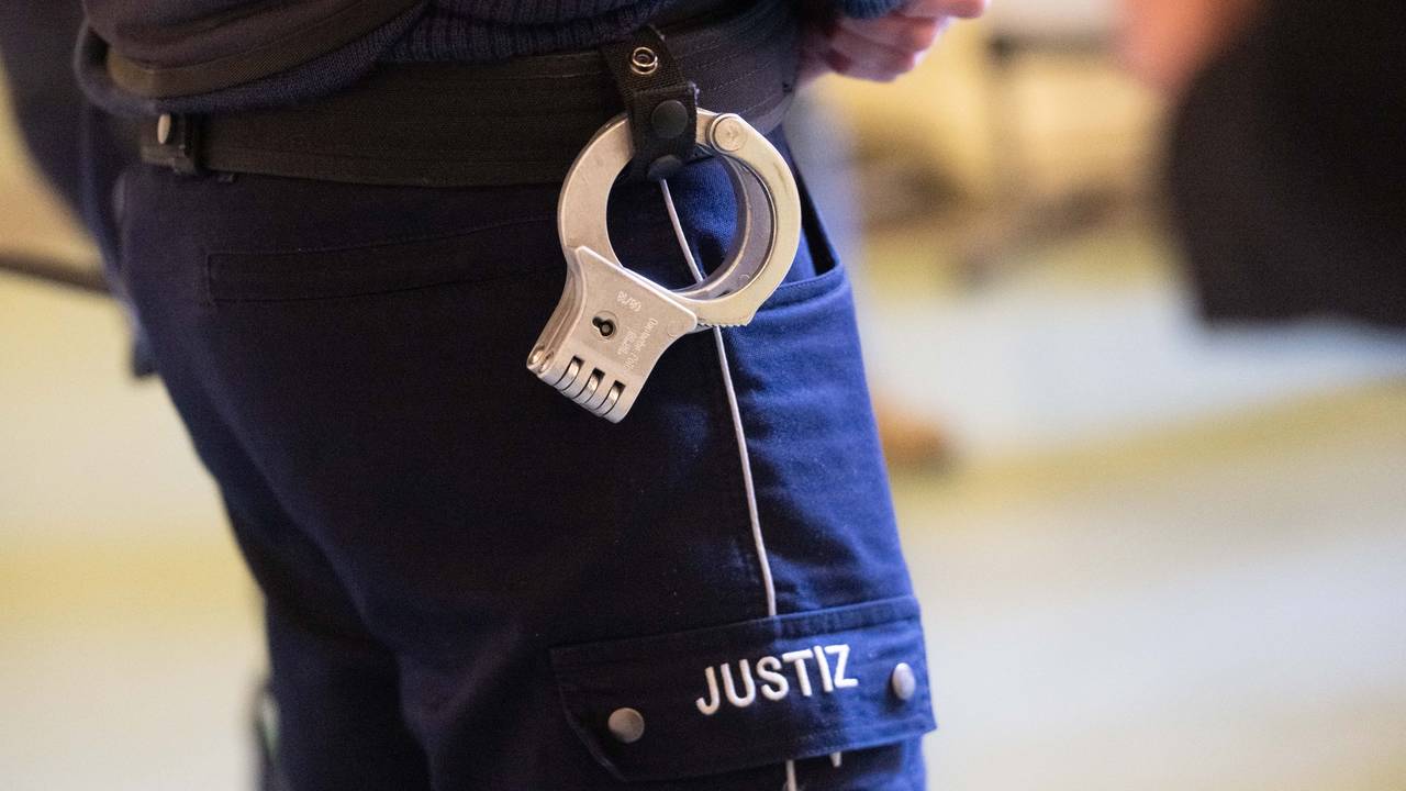 Ein Justizbeamter steht mit Handschellen im Verhandlungssaal eines Verwaltungsgerichts (Symbolfoto).