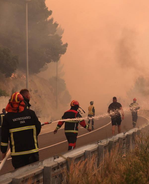 Feuerwehrleute löschen Brände neben einer Straße. Ein heftiger Vegetationsbrand wütet an der kroatischen Adria-Küste und führt dazu, dass viele Touristen fliehen.