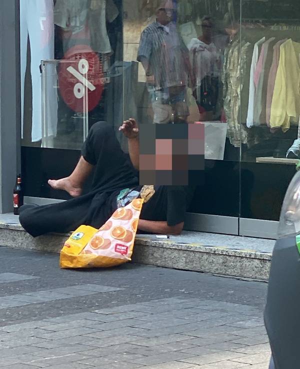 Ein Mann liegt vor einem Schaufenster.