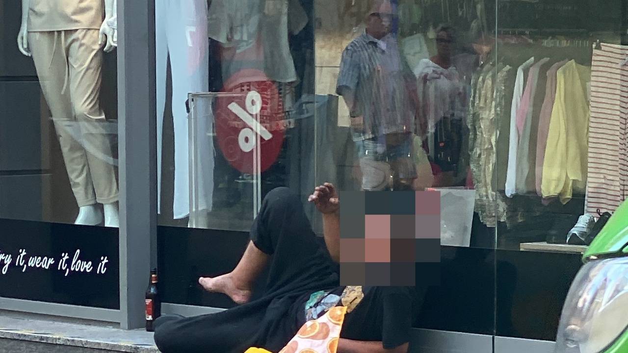 Ein Mann liegt vor einem Schaufenster.