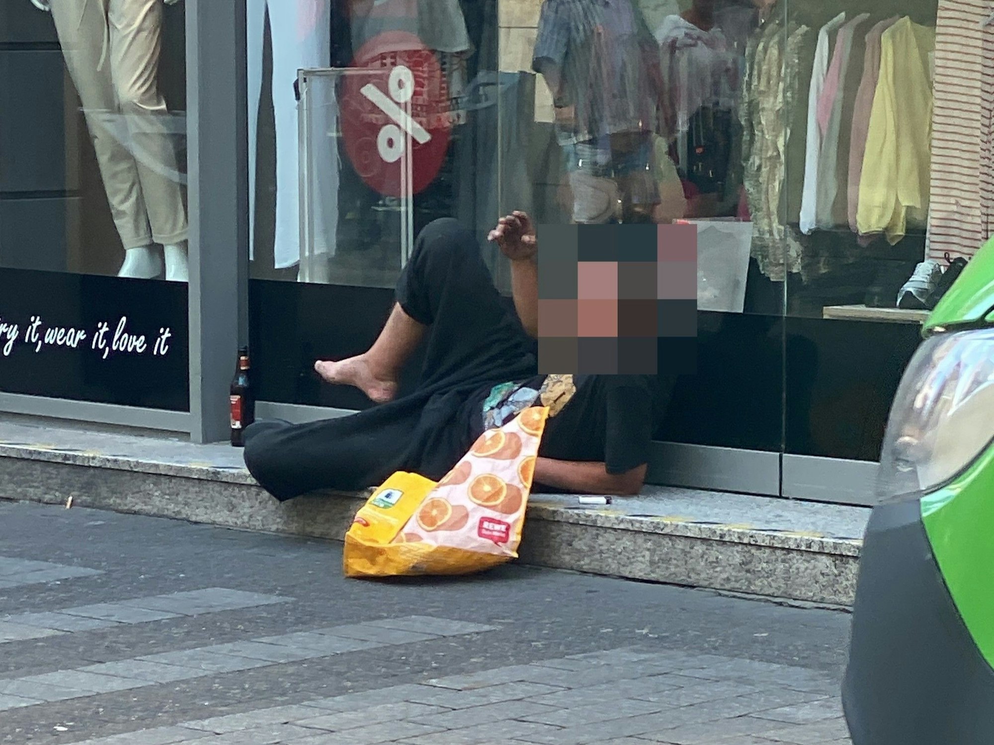 Ein Mann liegt vor einem Schaufenster.