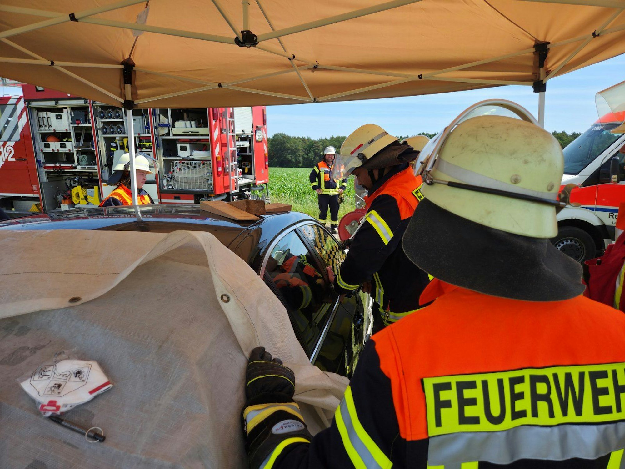 Mitarbeiter der Freiwillige Feuerwehren Visselhövede befreien die Kinder aus dem überhitzten Auto. Zuvor hatten die Einsatzkräfte ein schattenspendendes Zelt über dem Auto aufgebaut.